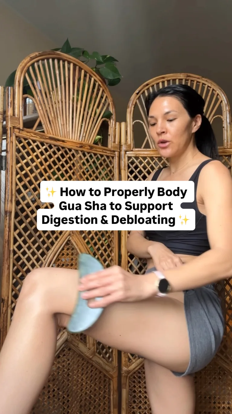 Level II: Detox lifestyle image with visible text reading “How to Properly Body Gua Sha to Support Digestion & Debloating” showing a person using a Sakara-branded body gua sha tool on their thigh while seated in front of woven rattan chairs.