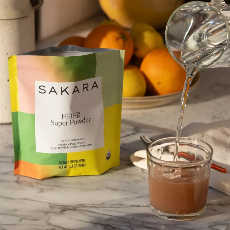 Bag of Sakara Fiber Super Powder on counter with water being poured into glass with Fiber Super Powder